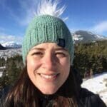 A woman with a green hat and snow covered trees